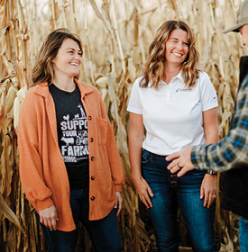 women in a corn field talking to man